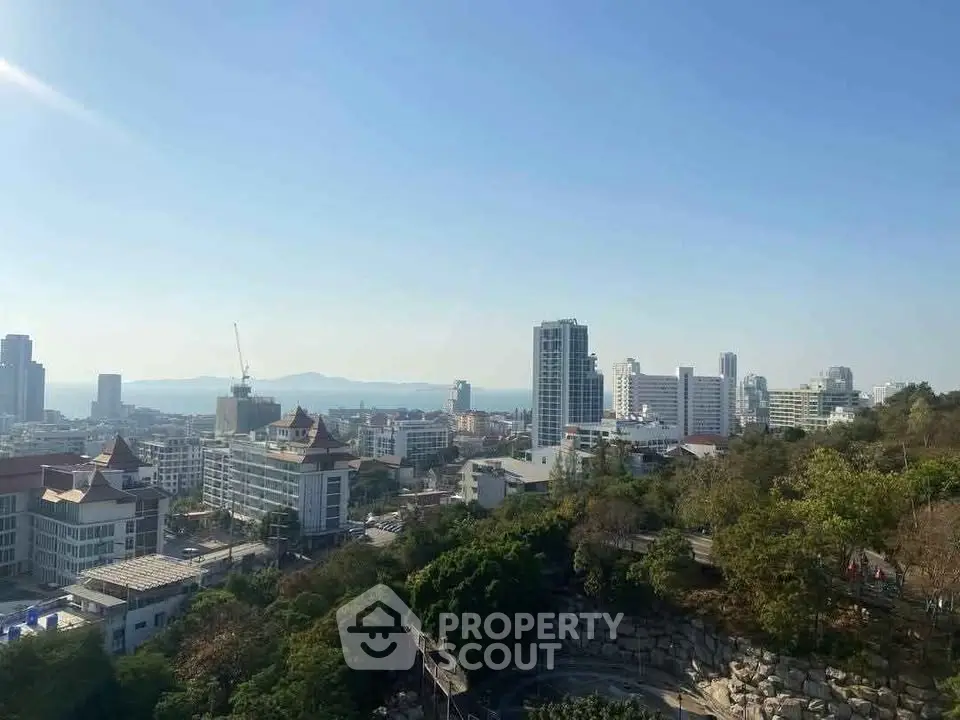 Stunning cityscape view with lush greenery and modern buildings under clear blue sky.