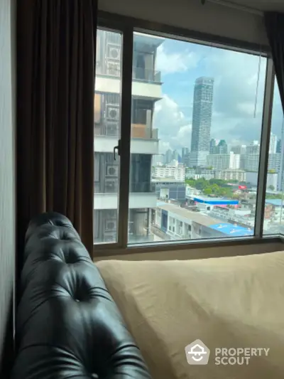 Modern bedroom with city view from large window in high-rise building