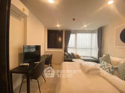 Modern bedroom with stylish decor and natural light, featuring a cozy seating area and workspace.