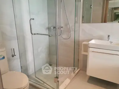 Modern bathroom with glass shower and sleek vanity in luxury apartment.