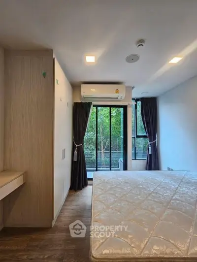 Spacious bedroom with large windows and balcony access in modern apartment
