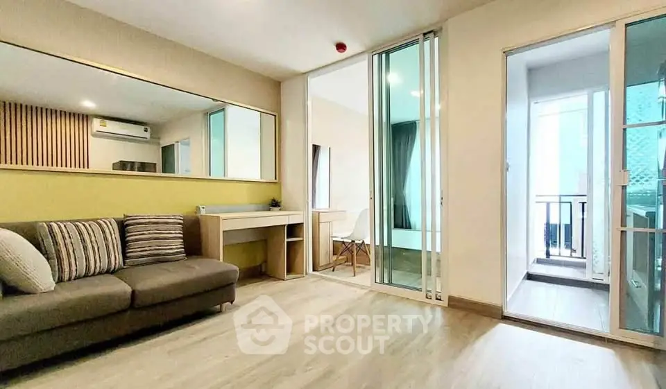 Modern living room with sliding doors leading to a cozy balcony, featuring stylish decor and ample natural light.