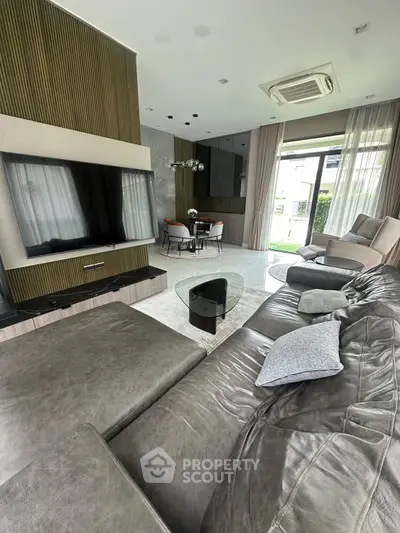 Luxurious living room with modern leather sofa and large TV, perfect for relaxation and entertainment.