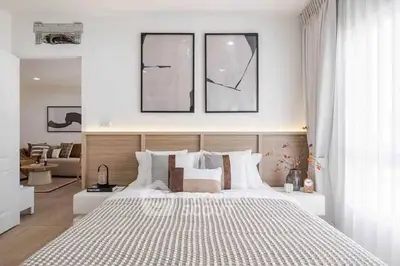 Modern bedroom with stylish decor and natural light, featuring cozy bedding and contemporary artwork.