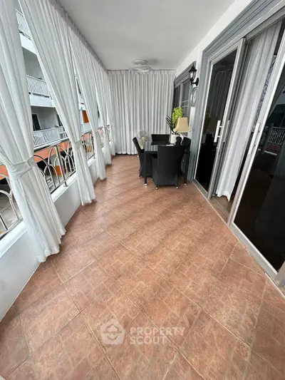 Spacious balcony with elegant curtains and outdoor seating in a modern apartment.