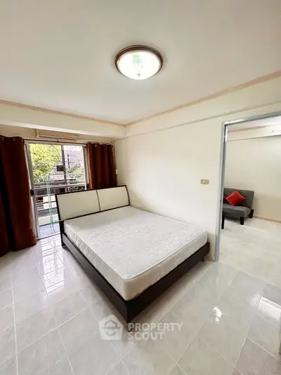 Spacious bedroom with large window and balcony access in modern apartment.