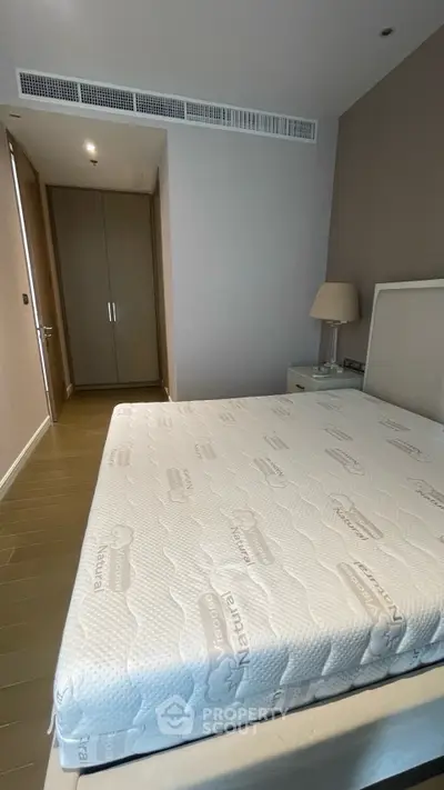 Spacious bedroom with modern design and natural light, featuring a comfortable mattress and built-in wardrobe.