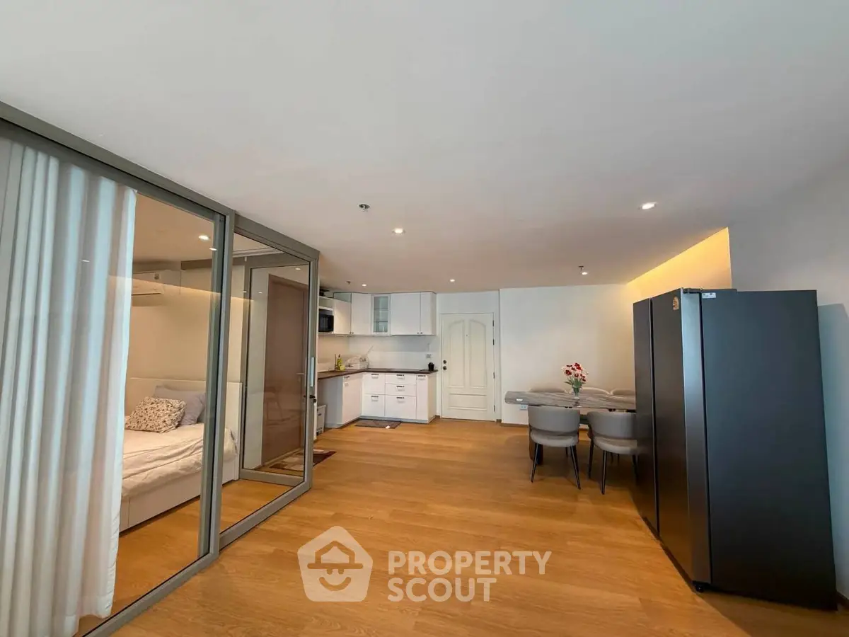 Modern open-plan living room with kitchen and dining area, featuring wooden flooring and sleek design.