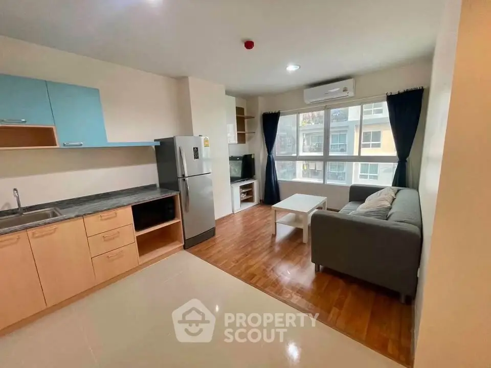 Modern open-plan living room with kitchen, featuring sleek appliances and cozy seating area.