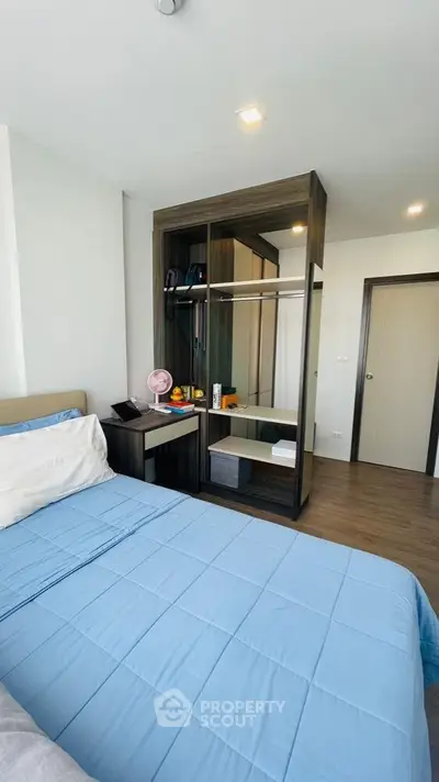 Modern bedroom with stylish wardrobe and cozy blue bedding in a contemporary apartment.