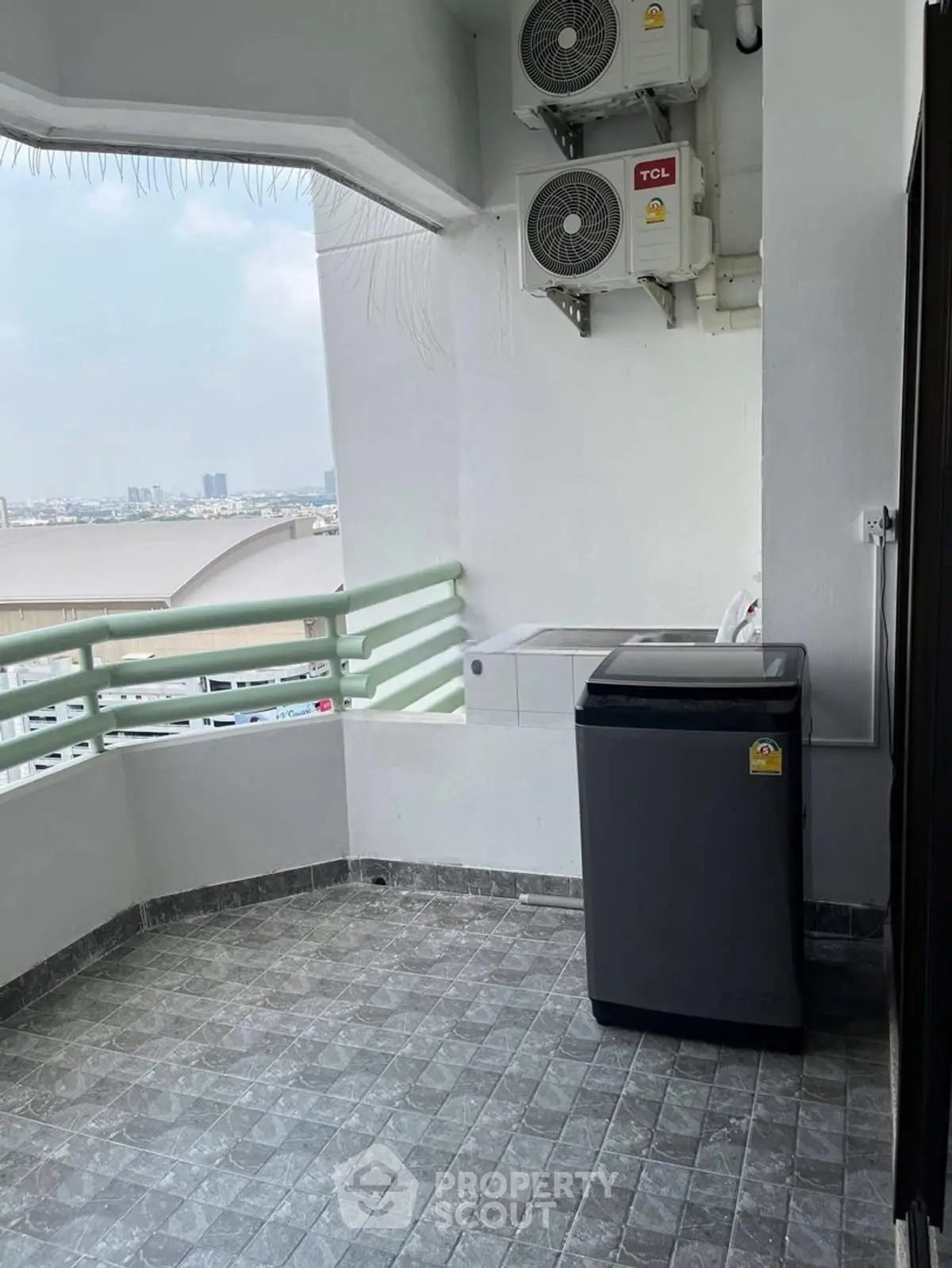 Spacious balcony with washing machine and city view, perfect for laundry and relaxation.