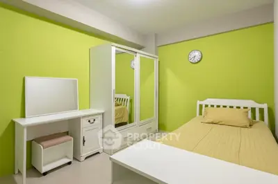Bright bedroom with green walls, white furniture, and a cozy bed, perfect for relaxation.