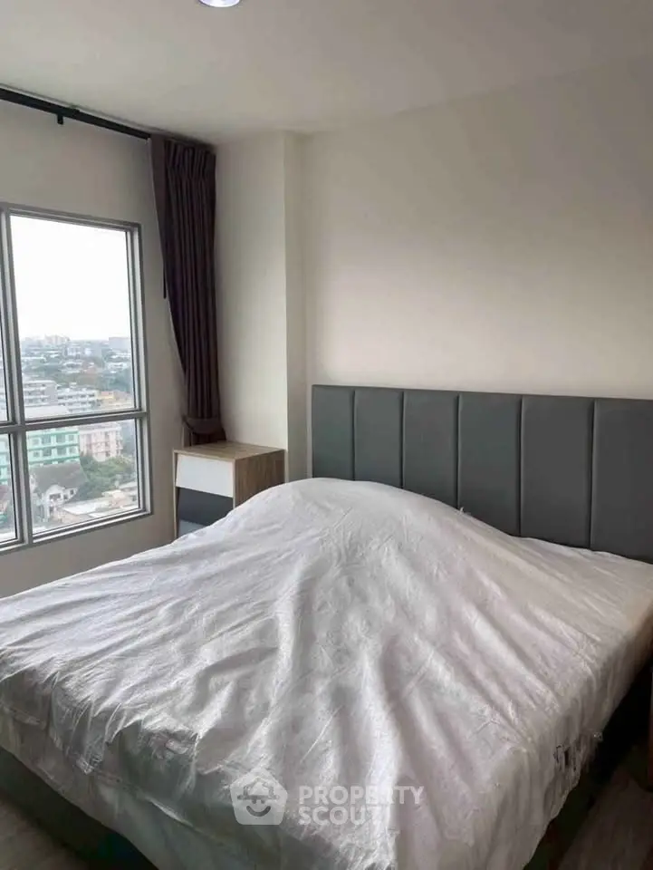 Cozy bedroom with large window offering city views and modern furnishings.