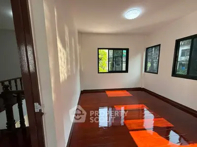 Spacious room with polished wooden floors and large windows for natural light.