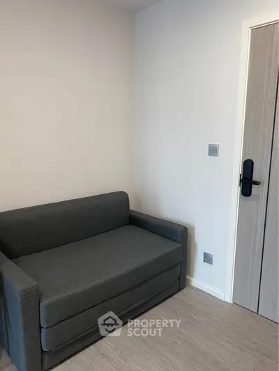 Modern minimalist room with sleek gray sofa and stylish door, perfect for cozy living.