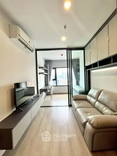 Modern living room with sleek design and city view, featuring leather sofa and wall-mounted TV.