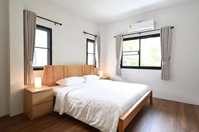 Spacious bedroom with wooden flooring and modern furnishings in a bright, airy apartment.