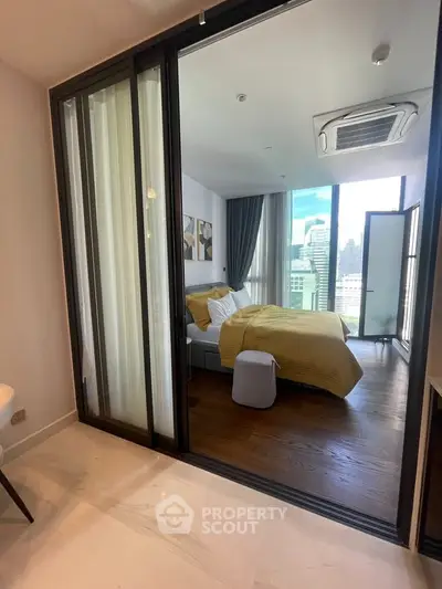 Modern bedroom with city view, featuring large windows and stylish decor in a high-rise apartment.