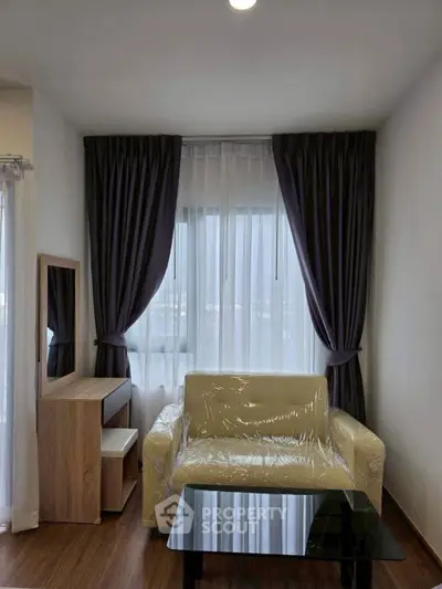 Cozy living room with modern furniture and large window with elegant curtains.