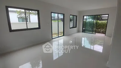 Spacious modern living room with large windows and glossy floors in a contemporary home.