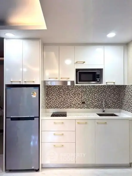 Modern kitchen with sleek white cabinets, built-in microwave, and stylish backsplash.