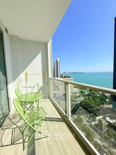 Stunning high-rise balcony with ocean view and modern green furniture.