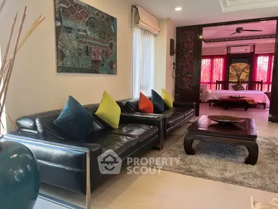 Luxurious living room with leather sofas and vibrant decor leading to a stylish bedroom.