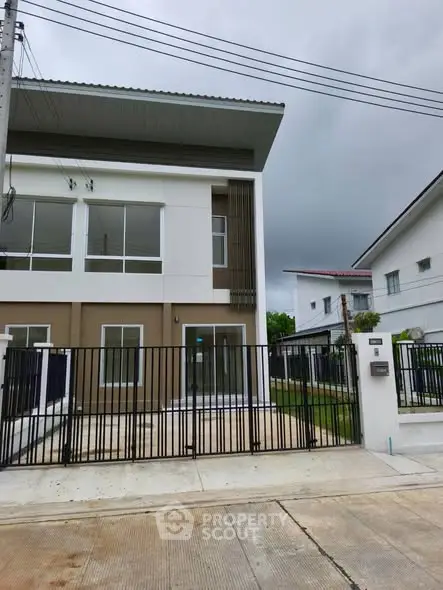 Modern two-story house with sleek design and gated entrance in suburban neighborhood.