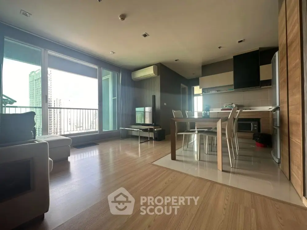 Modern open-plan living room with kitchen and balcony view in high-rise apartment