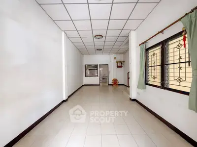 Spacious empty room with tiled floor and large window, ideal for customization.
