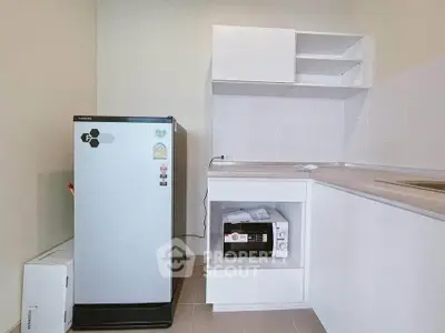 Modern kitchen with sleek fridge and built-in microwave in a compact layout.