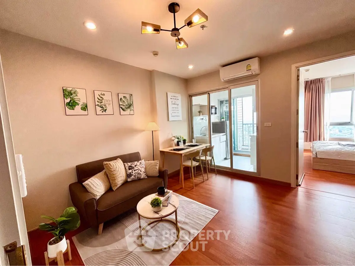 Modern living room with cozy decor and open layout leading to a bedroom, featuring stylish furniture and warm lighting.