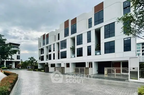 Modern multi-story residential building with sleek design and spacious parking area.