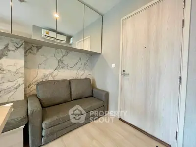 Modern living room with stylish sofa and marble accent wall in cozy apartment.