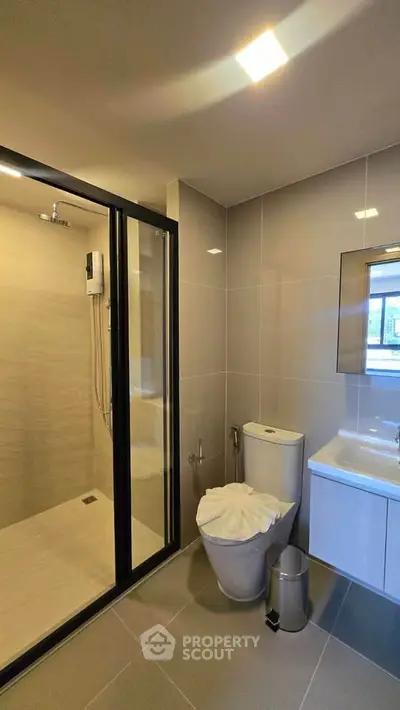 Modern bathroom with glass shower and sleek fixtures in contemporary apartment.