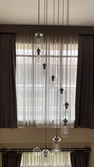 Elegant high ceiling with modern pendant lights and large windows in a luxurious living space.