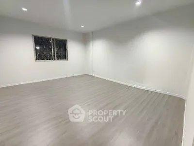 Spacious empty room with wooden flooring and bright lighting, perfect for customization.