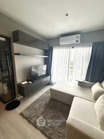 Modern living room with sleek furniture and large window offering natural light.