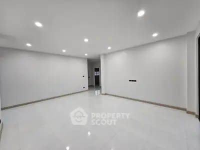 Spacious modern living room with sleek white tiles and recessed lighting.
