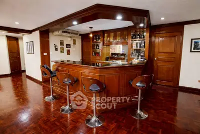 Luxurious home bar with wooden cabinetry and stylish bar stools in elegant living space.