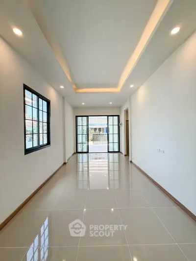 Spacious modern living room with sleek tile flooring and large windows for natural light.
