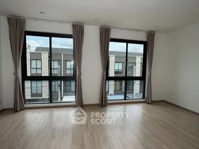 Spacious empty room with large windows and wooden flooring, offering ample natural light and modern design.