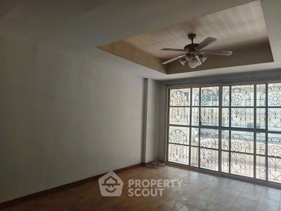 Spacious living room with ceiling fan and large windows offering natural light.