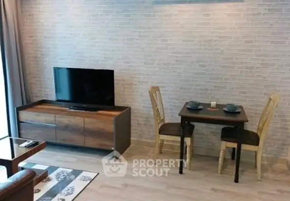 Modern living room with TV and dining set, featuring stylish brick wall and wooden flooring.