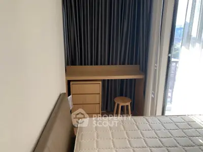 Cozy bedroom with desk and stool near window, ideal for work or study.