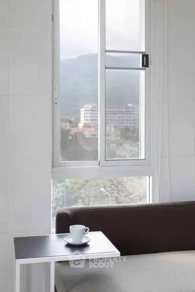 Cozy living room with scenic mountain view through large window, featuring modern sofa and coffee table.