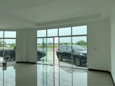 Spacious modern living room with large windows and sleek tile flooring, offering a bright and airy ambiance.