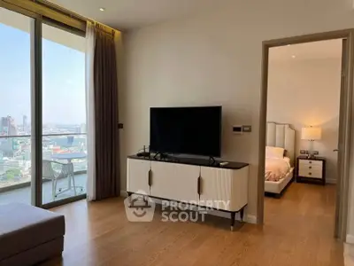 Modern living room with city view, large TV, and elegant decor in a high-rise apartment.