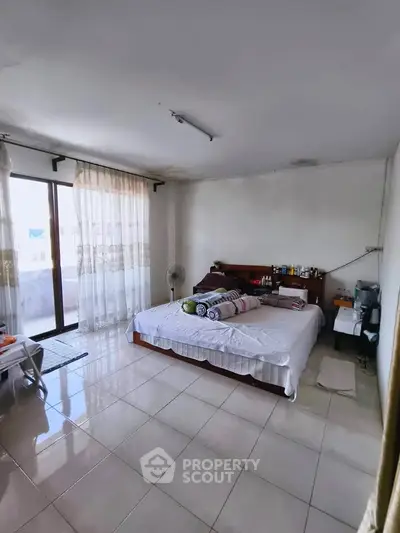 Spacious bedroom with large windows and balcony access, offering ample natural light and a cozy atmosphere.