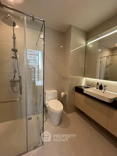 Luxurious modern bathroom with glass shower and sleek fixtures in upscale apartment.